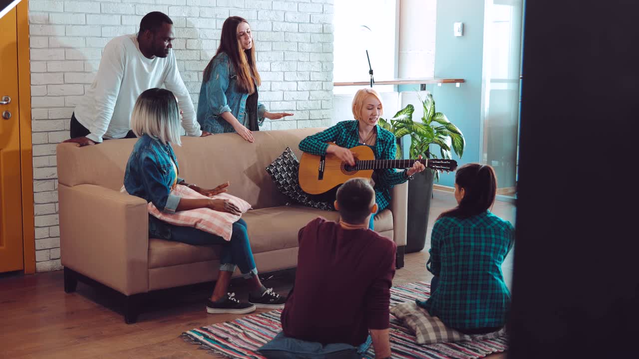 기타와 함께 파티를 즐기고 큰 현대 아파트에서 휴식을 취하는 다국적 사람들