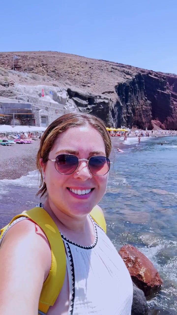 Iloinen vloggaaja kuvaamassa selfie-videota Punaisella rannalla Santorinilla