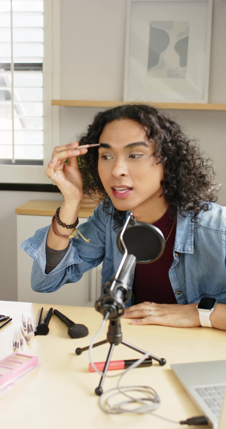 Wideo pionowe: Osoba niebinarna, vlogger/ka sięgająca po pędzelek do brwi, wypełniająca brwi w studiu do tutorialu