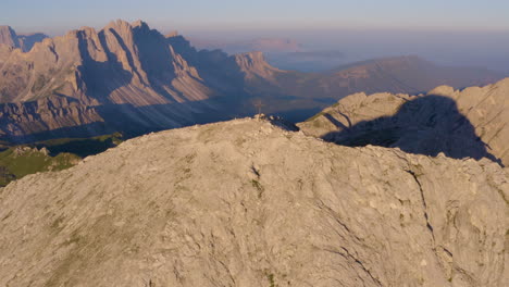 Aerial-view-above-individual-cross-on-South-Tyrol-Plose-Peitlerkofel-Dolomites-mountain-peak-overlooking-extreme-valley-below