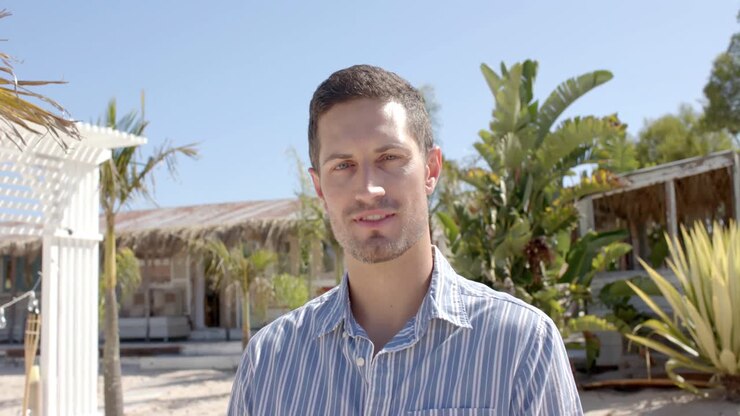 Portrett av en lykkelig kaukasisk mann som ser inn i kameraet ved strandhuset.