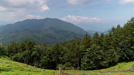 Fast-moving-timelapse-with-clouds-casting-shadows-on-mountains-with-forest-and-greenery-in-foreground---locked-off-shot