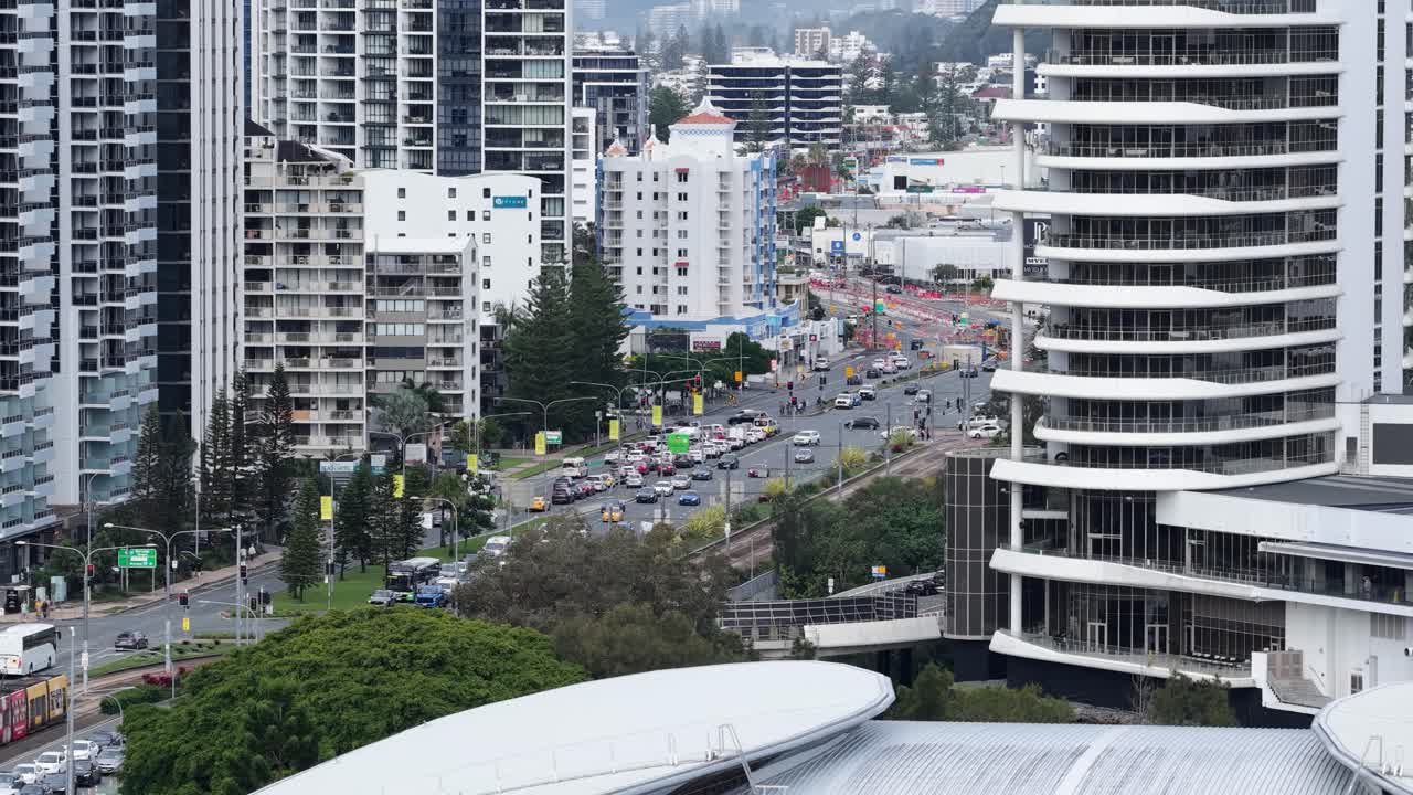 Aerial footage captures bustling city traffic amidst skyscrapers in Gold Coast, Australia, under overcast skies