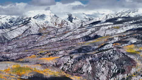 kebler pass aerial cinematic drone afternoon crested butte gunnison colorado seasons collide early fall aspen tree red yellow orange forest winter first snow powder rocky mountain peak circle right