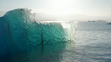 Erstaunliche-Drohnenansicht-Des-Eisbergs,-Der-An-Einem-Sonnigen-Tag-Auf-Der-Breidamerkurjokull-Gletscherzunge-In-Island-Glänzt.-Hintergrundbeleuchteter-Eisberg-Aus-Der-Vogelperspektive-Mit-Einer-Reihe-Von-Blautönen-Und-Interessanten-Formen-Und-Mustern