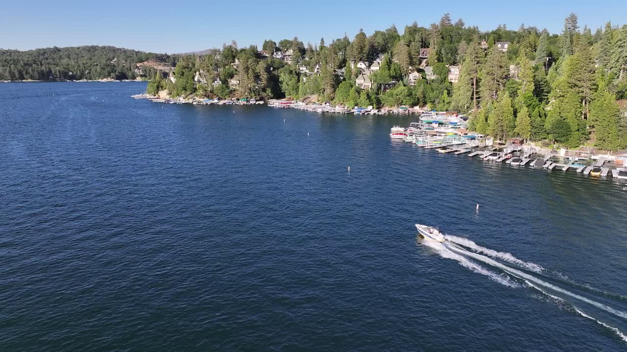 following a speed boat on lake arrowhead california with a view of lakeside homes and docks sunny day AERIAL TRUCKING PAN