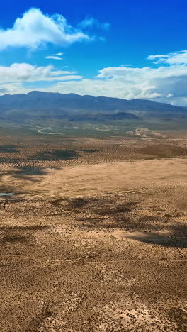 amazing scenery of a desert in california. dry lifeless landscape of death valley under the azure sky with white clouds. top view. vertical video