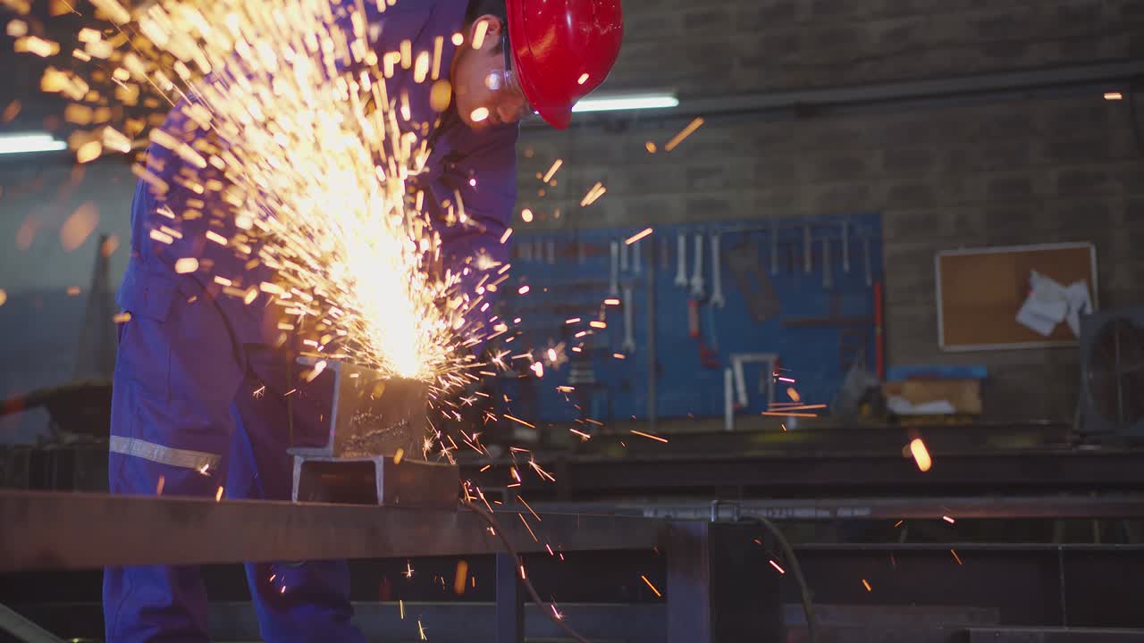 asian male technician worker in a safty uniform wear welders leathers,Electric wheel grinding on steel structure in factory workshop in the garage, orange bokeh sparks fly to the sides