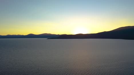 sol saliendo sobre el lago con la silueta de las montañas en el fondo