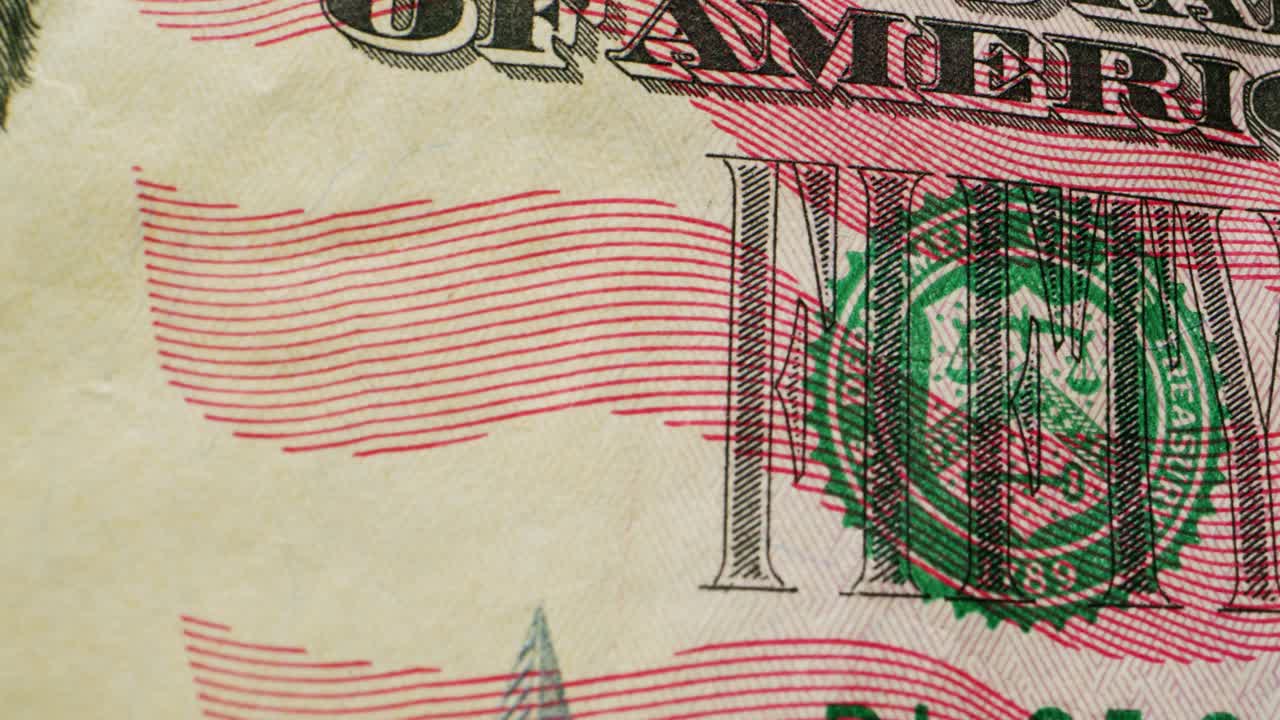 A closeup view of a fifty dollar bill on a polished wooden table, highlighting its intricate design