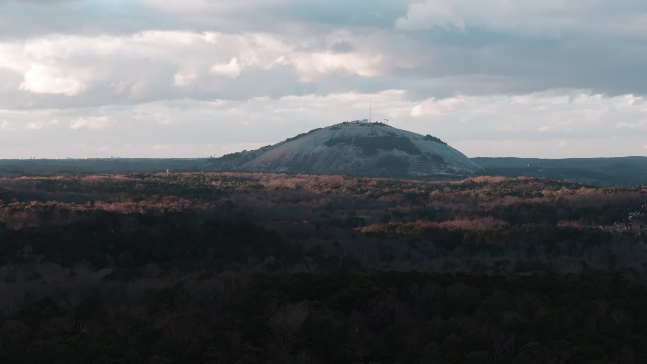조지아 주 스톤 마운틴 파크 (stone mountain park, georgia) 에 있는 스톤마운틴의 드론 영상으로 푸른 나무와 떠다니는 구름으로 가득 찬 웅장한 산을 보여준다.