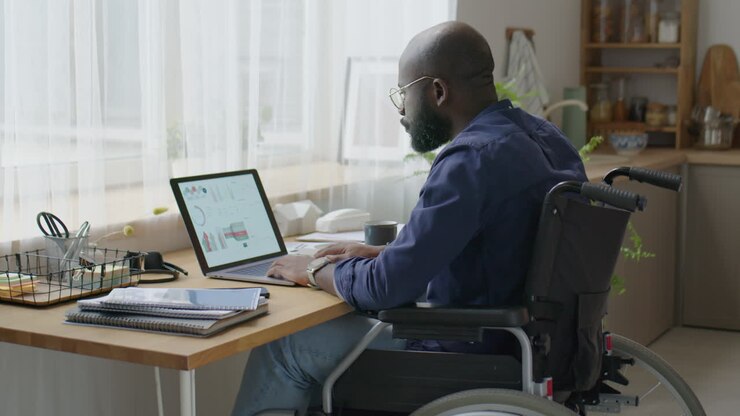 Black Businessman in Wheelchair Working on Laptop at Home