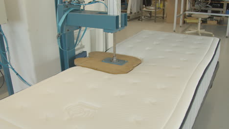 Wooden-butt-shaped-press-testing-quality-of-new-mattress-in-testing-facility---medium