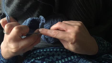 woman crocheting a small blue bag at