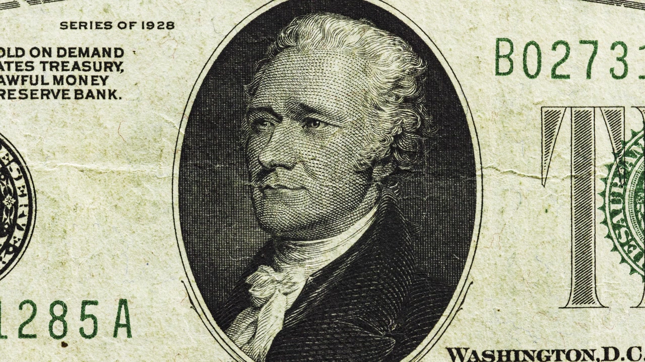 Close pan of an old and worn U.S. ten dollar note showing oval portrait and aged paper texture