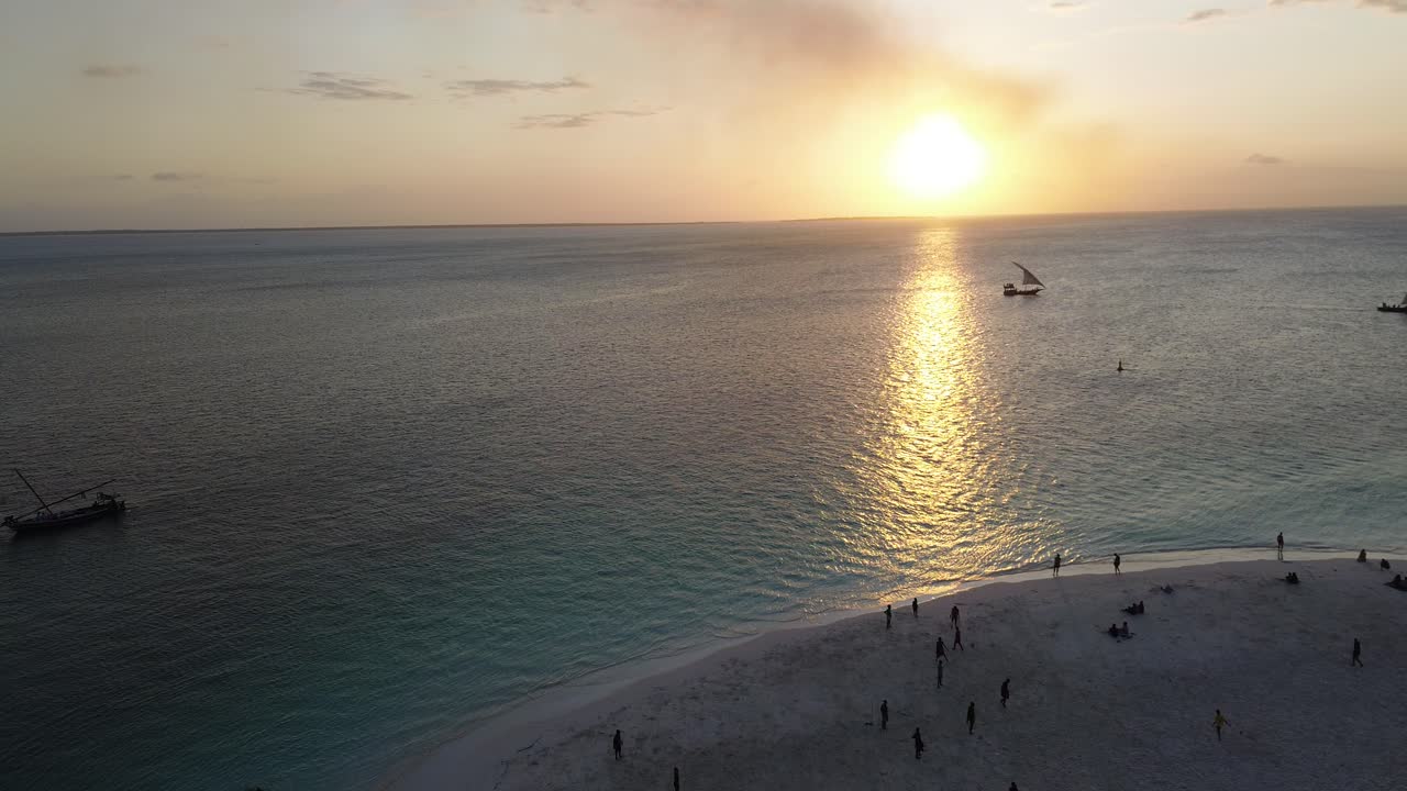 Sunset over Tropical Island Beach with Boats and People