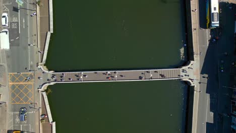 overhead, downwards aerial video of the river liffey, various bridges and dublin city centre in dublin, ireland on a bright and sunny day. filmed in 4k, 60fps and with rec709 color.