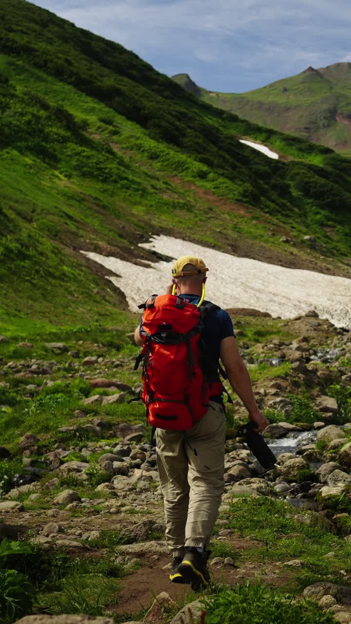 Uomo con zaino che fa trekking su un sentiero di montagna in estate