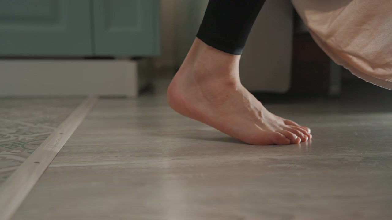 Passo giocoso a piedi nudi sulle piastrelle, sollevamento e falcata ritmici veloci, fruscio del lenzuolo, sfondo di mobili da cucina, tempo vivace come un amante della musica che balla, energia gioiosa, prospettiva ravvicinata del pavimento