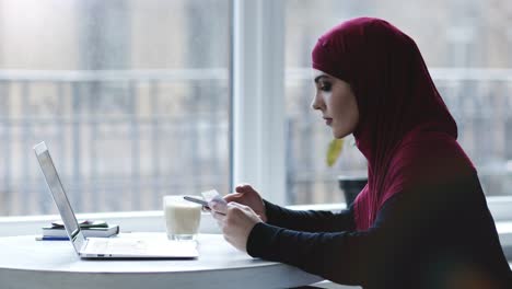 Indoors-footage-of-an-attractive-muslim-girl-using-different-gadgets-such-as-smartphone-and-laptop