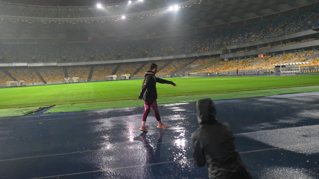 비가 오는 밤 에 경기장 의 은 트랙 을 고 있는 여자