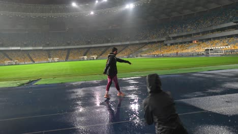 woman walking on the wet track at the stadium during a rainy night