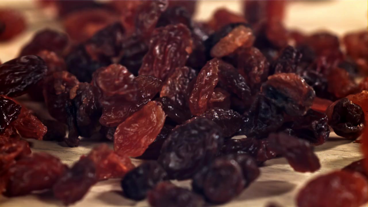 Ralenti de raisins secs et de baies tombant sur une surface en bois.