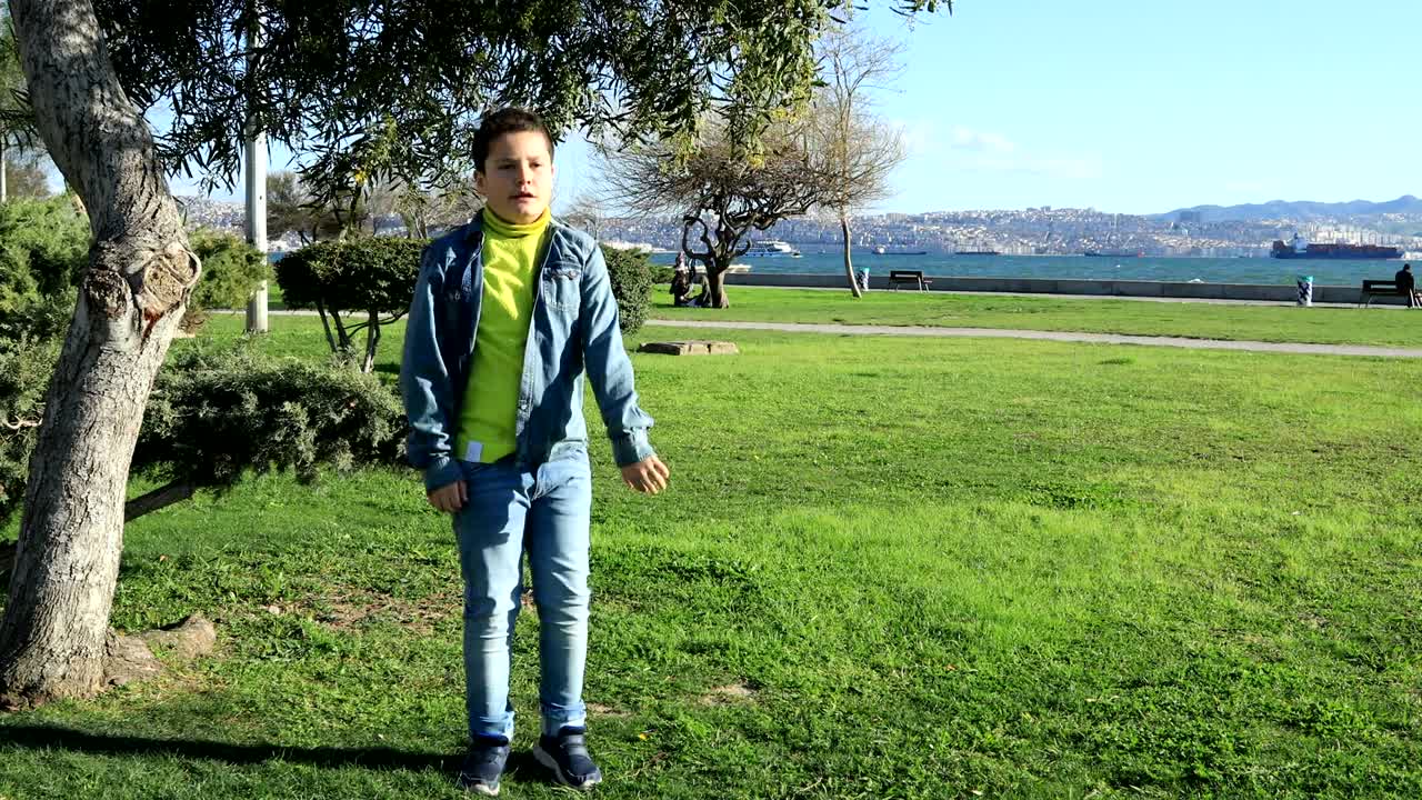 헤드폰을 들고 잔디에서 춤추는 어린 소년