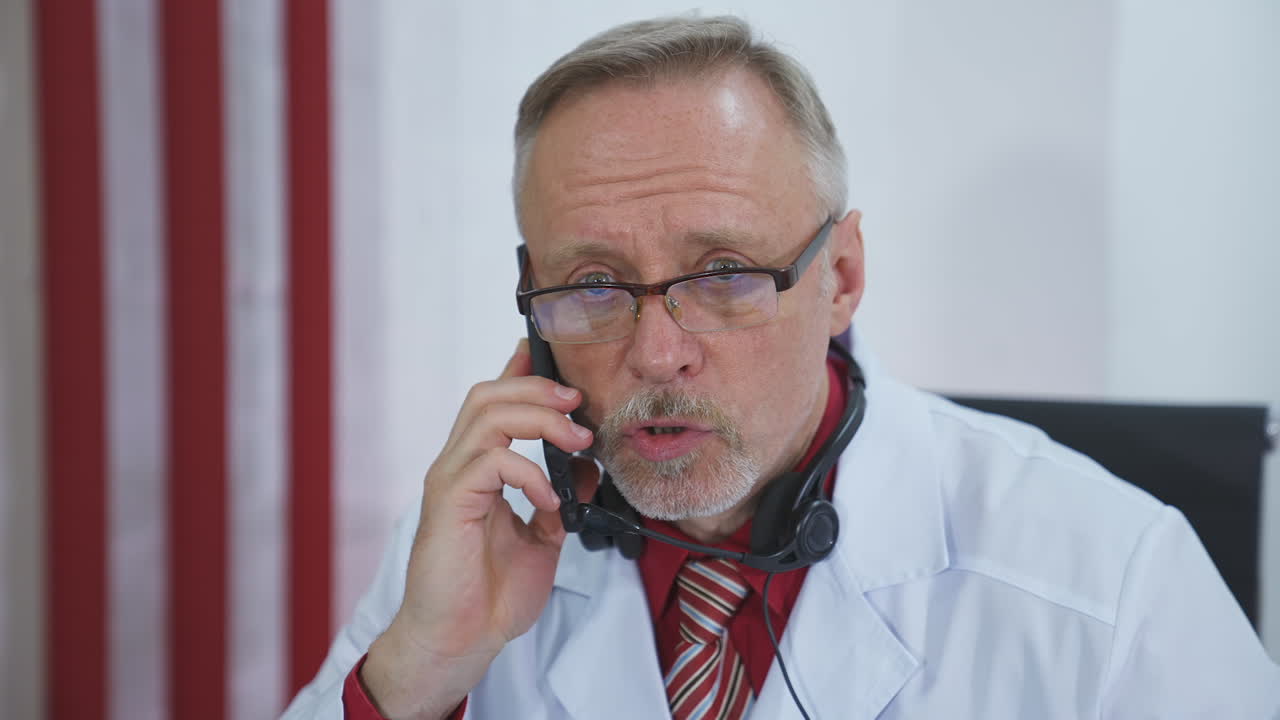 Medical consultation with a phone. Portrait of serious male doctor in lab coat talking on mobile phone in medical office. ?oncept of pandemic, modern medicine.