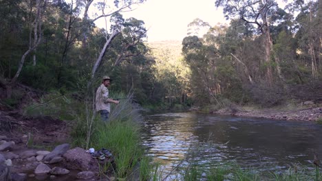 un hombre lanza un señuelo con una caña de pescar en un hermoso río aislado de alta montaña en australia