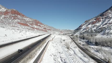 Following-vehicles-and-traffic-driving-along-I-70-in-the-mountains-with-fresh-snow-on-the-ground