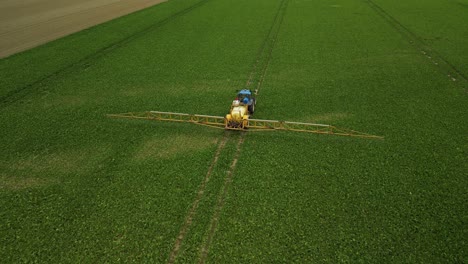 flying behind a tractor with a pull-type sprayer traveling in a straight line spraying crop protection products