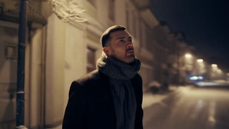 man walking in a snowy city at night