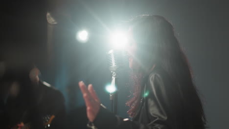 blurry view of a singer and guitarist performing in a dimly lit room, with bright lights shining on the singer's face, creating a dramatic and emotional atmosphere