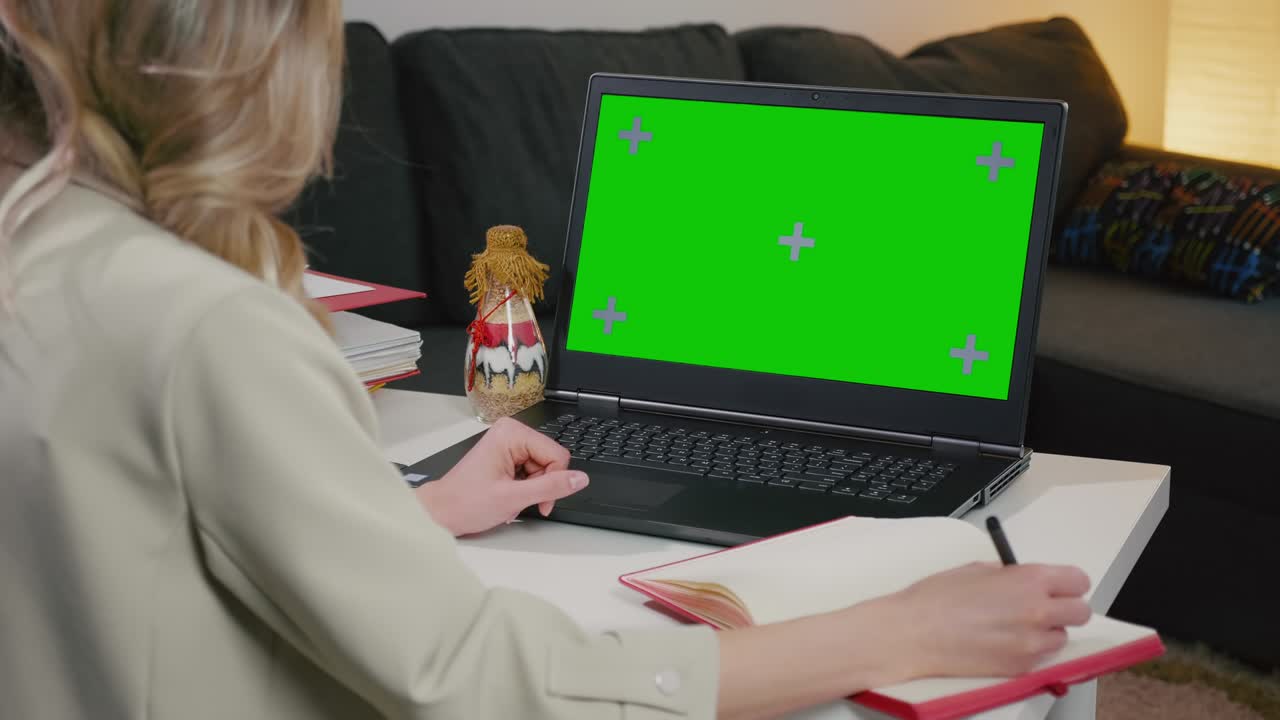 la mujer de negocios toma notas en el cuaderno de la computadora portátil con pantalla verde.