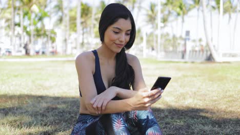 Pretty-sportswoman-using-phone-in-park