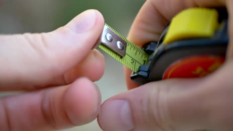 close up of a construction worker pulling out a yellow tape measure to check the dimensions for a lumber cut on a jobsite