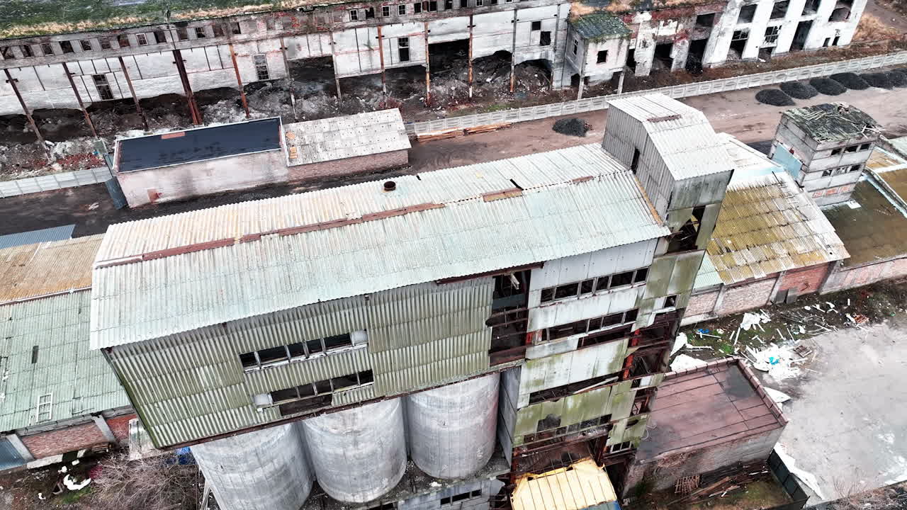 Old wrecks of chemical plant locality. Broken walls with huge holes and debris on the ground. Aerial view.