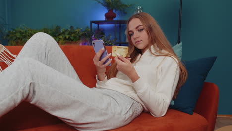 chica encantadora usando tarjeta de crédito y teléfono inteligente, transferir dinero, compras compras en línea