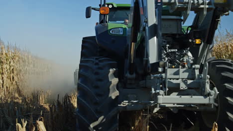 large green tractor working in a dusty agricultural field