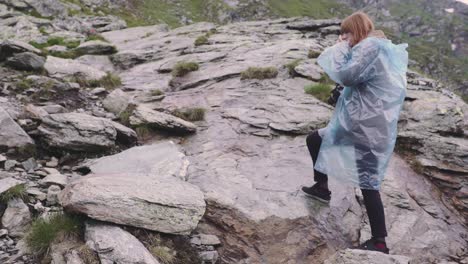 a young woman hiker climbs mountains and photographs landscapes on camera. transfagarasan, carpathian mountains in romania