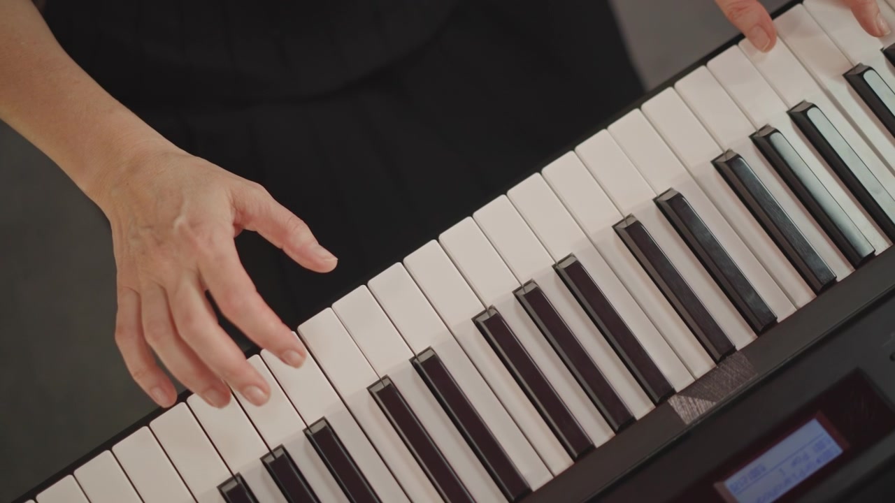 Insegnante caucasico che suona la tastiera digitale, studio in aula, dimostrando tecnica, diteggiatura, postura, schemi di accordi, concentrandosi sullo studente adulto, primi piani delle mani, tempo costante, illuminazione calda