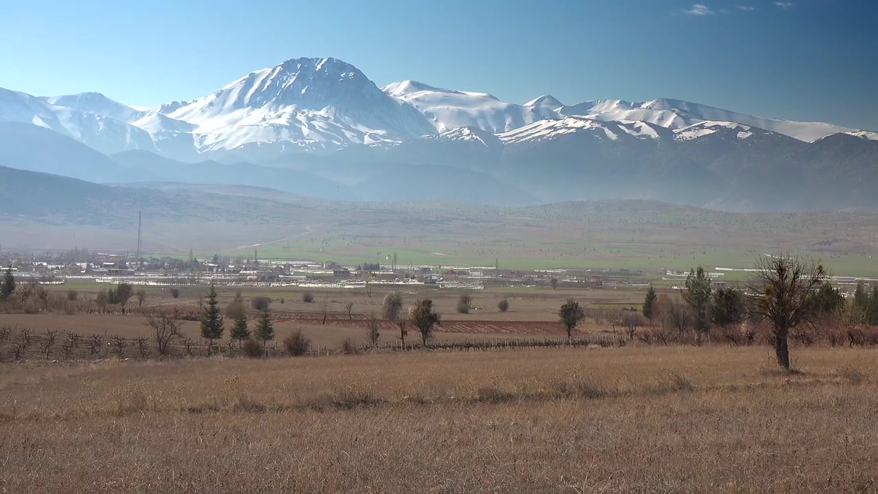 Vista panoramica di montagne innevate che dominano una valle rurale