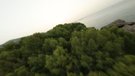 fpv aerial drone forward moving shot over resort along the rocky shore in cala punta negra, balearic islands, spain during evening time