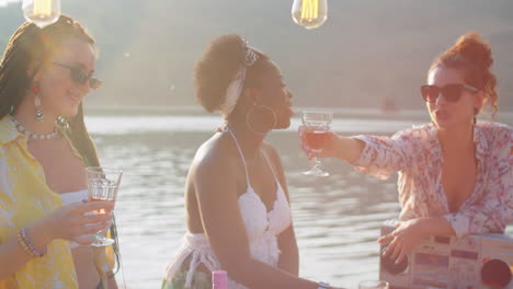 female friends drinking wine at summer lake party