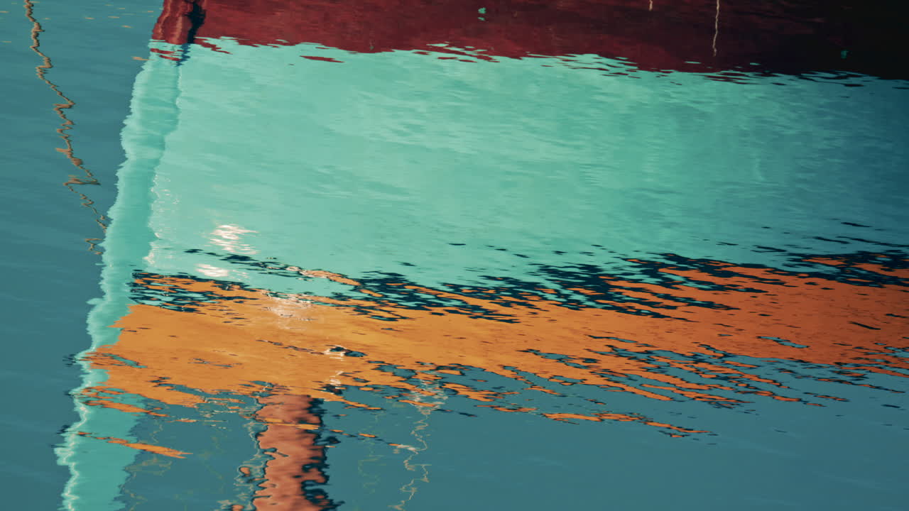 Abstract reflection of colorful boat hulls rippling across the surface of the water, creating a painterly effect