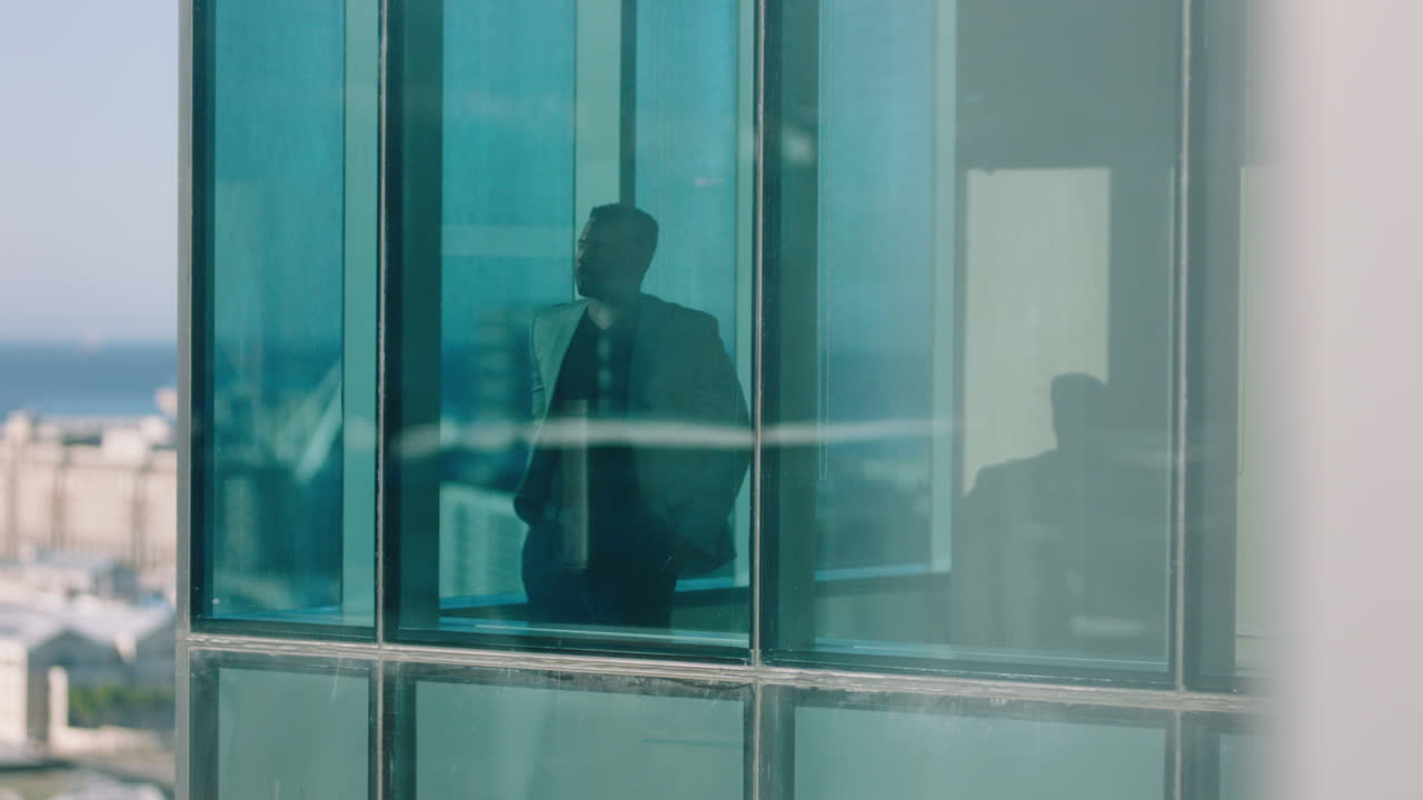 un uomo d'affari afroamericano di successo che guarda fuori dalla finestra, pianifica il futuro, pensa al futuro, gode della vista della città, filmati in 4k.