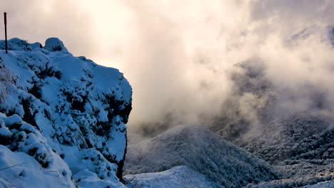 toma panorámica de excursionistas caminando por acantilados nevados con atmósfera mística con niebla y luz solar