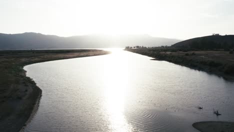 Sich-Langsam-Bewegender-Dolly-Neigungsschuss-Mit-Blick-Auf-Lake-Elsinore-Kalifornien-Westküste-USA-Während-Eines-Leuchtend-Gelben-Sonnenuntergangs-Sonnenaufgang-über-Der-Dunstigen-Bergkette