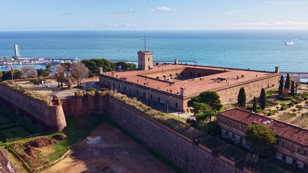 Un drone si dirige verso il castello di Montjuïc, rivelando le mura in pietra e il mare sullo sfondo a Barcellona